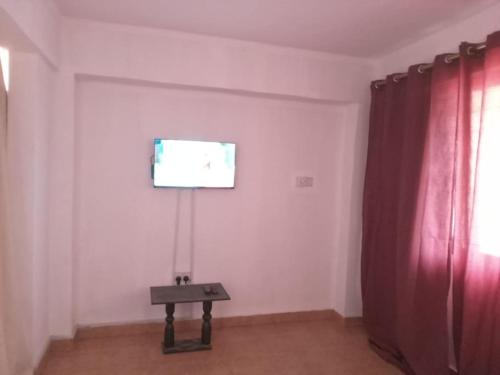 特马The Lord's residence的一间墙上配有电视和一张桌子的房间