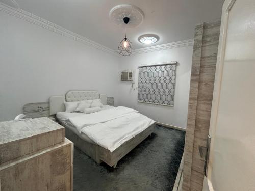 麦地那شقة العقيق عروة alaqeeq apartments的白色卧室配有一张床和一个吊灯