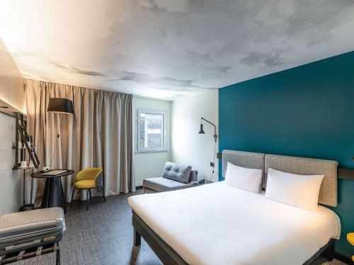 马拉加宜必思马拉加中心酒店的卧室配有一张白色大床和蓝色的墙壁