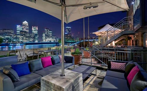 伦敦伦敦希尔顿逸林酒店 - 港口河畔的屋顶酒吧配有沙发,享有城市美景