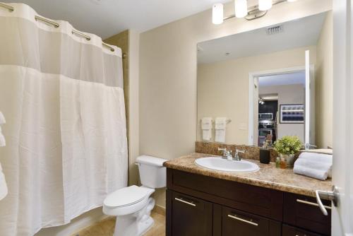 迈阿密Dharma Home Suites South Miami at Red Road Commons的一间带水槽、卫生间和镜子的浴室