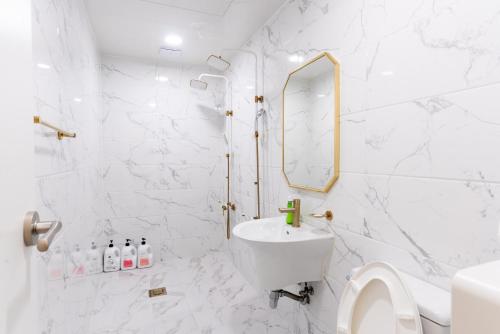 釜山The Wave Pension的白色的浴室设有水槽和镜子