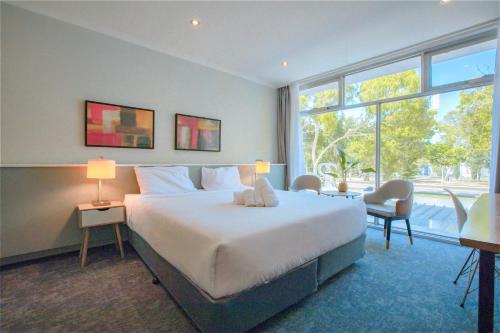 墨尔本The Parkmore Hotel的一间卧室设有一张大床和一个大窗户