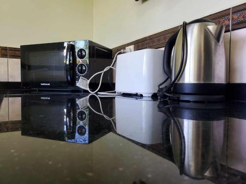阿皮亚LE RIC HOUSING LTD的厨房柜台配有咖啡机和微波炉