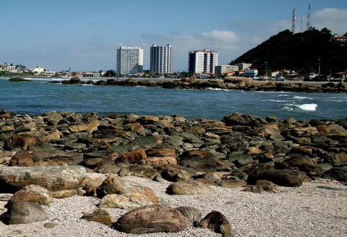 伊塔尼亚恩Apartamento na Praia dos Sonhos Perto do Mar em Itanhaém的靠近水面的海滩上的一群岩石