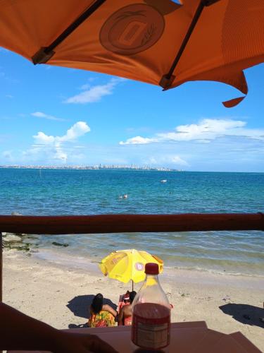 伊塔帕里卡Pousada Villa do Mar的两人坐在海滩上,被伞所环绕