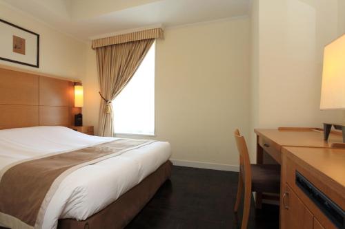 东京银座蒙特利拉苏瑞酒店的一间卧室配有一张床、一张书桌和一个窗户。