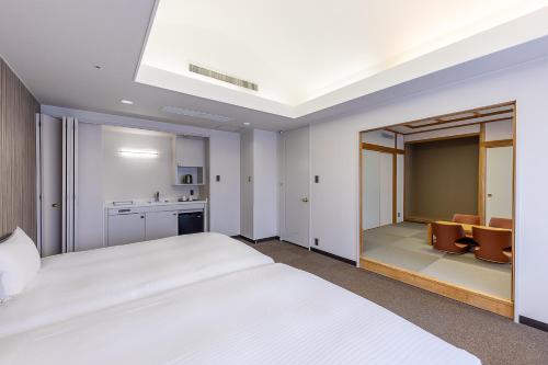 旭川旭川庭院酒店的一间带白色大床的卧室和一间厨房