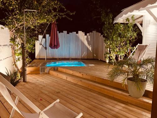 圣安尼Les Coulirooms - Suite avec jacuzzi et grande terrasse的一个带游泳池、两把椅子和遮阳伞的甲板