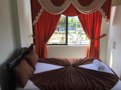 埃斯梅拉达斯Hotel Shekinah Internacional的窗前的一张床位,窗帘红色