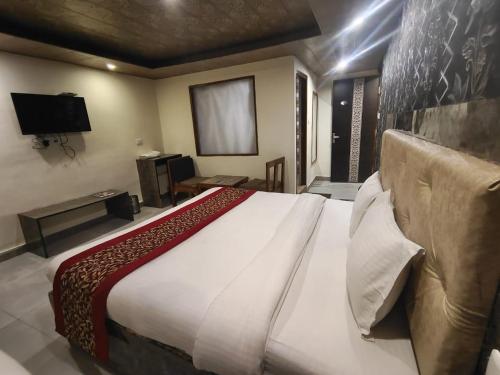 西姆拉Shimla Royale - Mountain Zest的一间卧室配有一张大床和电视