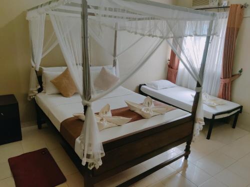 库鲁内格勒Grand Colonial Viveka的一间卧室配有两张带蚊帐的床