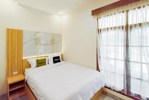 KedatonUrbanview Hotel Tritia Lampung的卧室配有白色的床和窗户。
