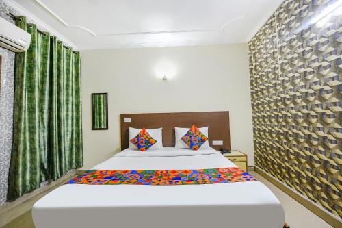 新德里FabExpress Smart Stay的卧室配有一张带彩色枕头的大型白色床。