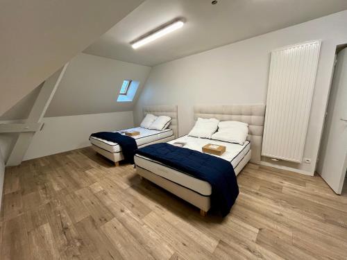 奥登河畔的布雷特维尔Superbe Maison de maître 10 chambres 300 m2 Caen的小型客房铺有木地板,配有两张床。