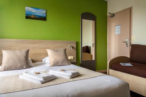 Plurien伯恩卡普酒店的一间拥有绿色墙壁的卧室和一张带两条毛巾的床
