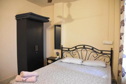 波戈马洛Valerys Nest Bogmalo - Private villa near the beach and Dabolim airport的一间卧室配有一张带两个白色枕头和黑色橱柜的床。
