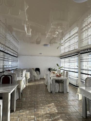DzhergalanDolinka Lodge的用餐室配有白色的桌子和白色的椅子