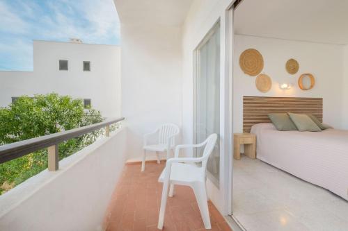 圣埃乌拉利亚阿祖拉尼地中海酒店的一间白色卧室,配有床和阳台