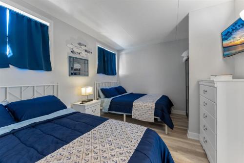 北怀尔德伍德2200 Atlantic Ave, Unit 105的卧室内的两张床,配有蓝色的床单和蓝色的窗帘