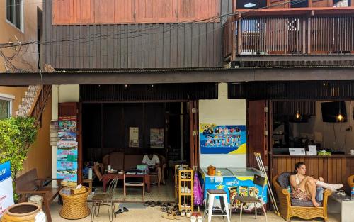 塔林甘海滩Aforetime House @ Samui的坐在建筑物外椅子上的男人