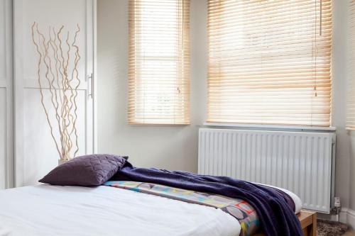 伦敦Madison Hill - Fernlea Garden 2 - One bedroom home的一间卧室配有一张床和两个百叶窗的窗户