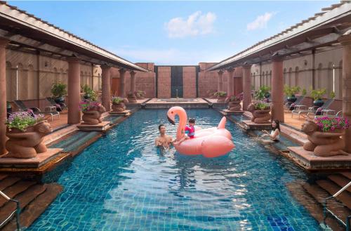 曼谷Crowne Plaza Bangkok Lumpini Park, an IHG Hotel的游泳池,有粉红色的火烈鸟和水中的人