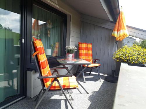 HerscheidFerienwohnungen Bußmann的庭院配有两把椅子、一张桌子和一把遮阳伞