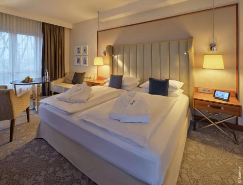 波恩Dorint Hotel Bonn的酒店客房设有一张大床和一张桌子。