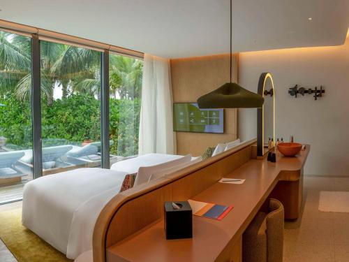南马累环礁SO/ Maldives的一间卧室配有一张床、一张书桌和一个窗户。