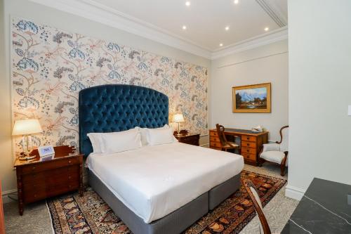 约翰内斯堡The Monarch Hotel的一间卧室配有一张大床和蓝色床头板