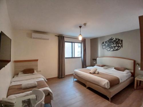 安曼Layaali Amman Hotel的一间卧室设有两张床和窗户。