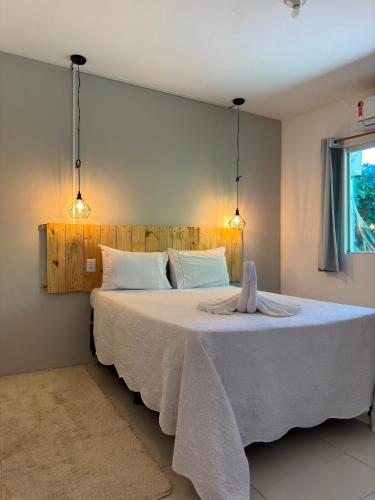 伊塔卡雷Pituba Ville - Ap - 1 andar - 2/4的卧室配有一张带两个灯的大白色床