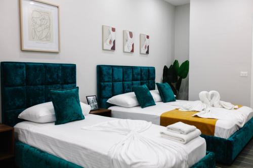 都拉斯Andor Luxury Hotel的绿白色客房内的两张床