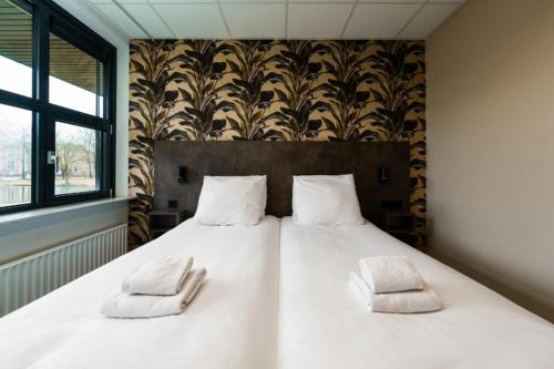 瓦赫宁根Hotel WICC的一张白色的大床,上面有两个白色的枕头