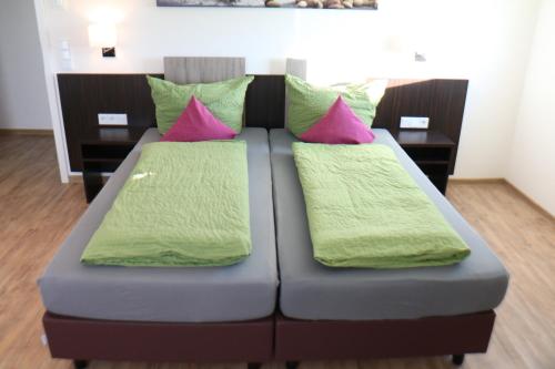 腓特烈港Hotel Gästehaus Stock的一张蓝色的床,上面有粉色和绿色的枕头