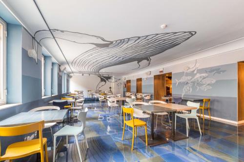 热那亚Ostello Bello Genova的餐厅设有桌椅,天花板上涂有鲸鱼