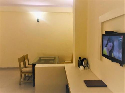 斋浦尔Tulip Palm的一间设有桌子的房间和墙上的电视