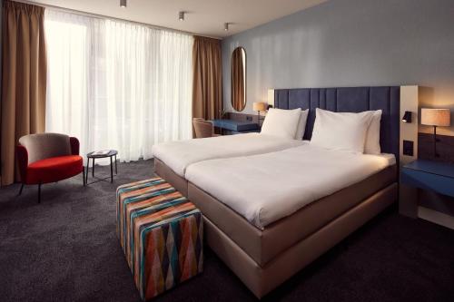 希佛萨姆凡德瓦克酒店的酒店客房设有一张大床和一张红色椅子。