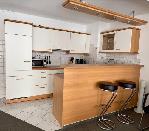 罗拉赫索捏茨卡度假公寓的厨房配有白色橱柜和2张凳子