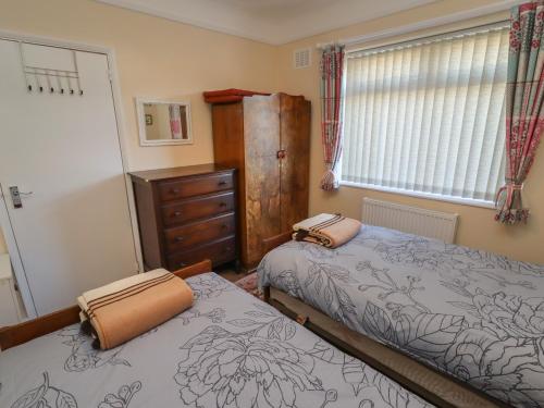 切斯特4 Venables Road的一间卧室设有两张床、一个梳妆台和窗户。