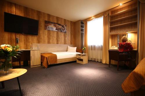 皮拉福马酒店的一间酒店客房,配有一张床,还有一位坐在椅子上的人