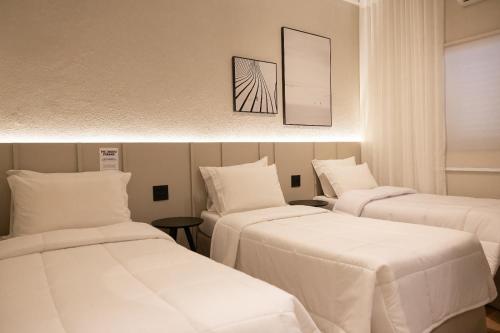 弗朗卡Morada Inn Hotel的配有白色床单的客房内的两张床