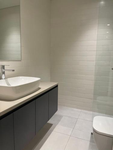 沙迦1 BR Luxury Apt by AJ Aljada的白色的浴室设有水槽和卫生间。