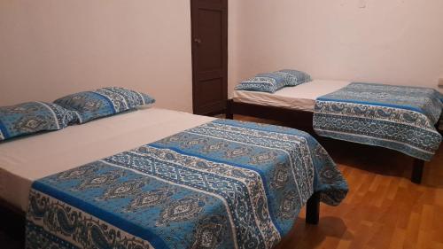 莱昂Hotel Sansívar的一间设有三张床的房间,配有蓝色和白色的盖子
