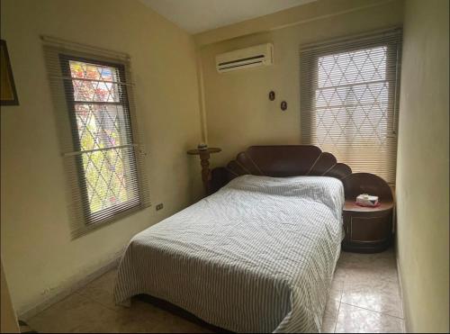 圣克里斯托瓦尔Casa en San Cristóbal, urb los naranjos的一间卧室设有一张床和两个窗户。