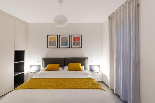 Monte CeneriMarAvilia Apartment - Vicino a Lugano的一间卧室配有一张大床和两张黄色枕头
