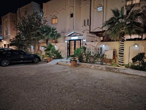麦地那Khair Jewaar Apartments Al Madinah的夜间停在大楼前的汽车