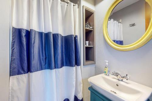 GraylandBreakwater Inn - Mastodon Cottage #G的浴室设有蓝色和白色的浴帘和水槽