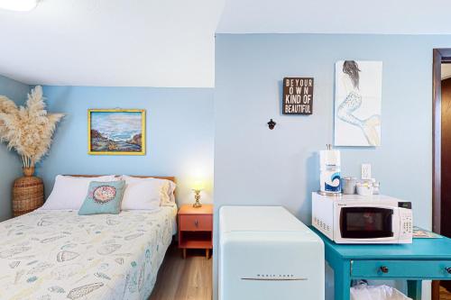 GraylandBreakwater Inn - Towhee Cottage #F的一间卧室配有一张床和一张桌子上的微波炉